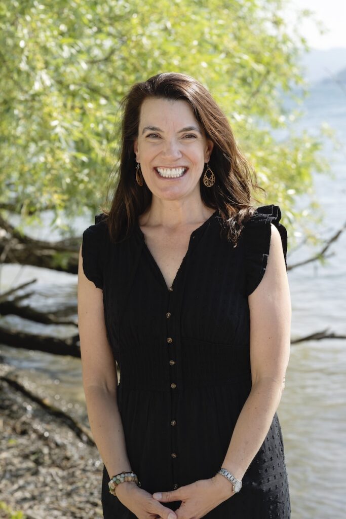 An outdoor photo of Jill Lamb in front of trees and a lake